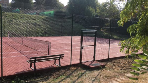 Un Court De Tennis Avec Une Clôture Verte Et Des Arbres En Arrière